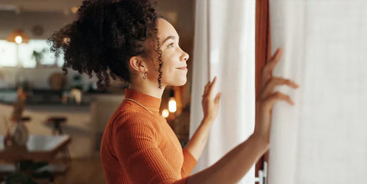Woman opening curtains on a new day