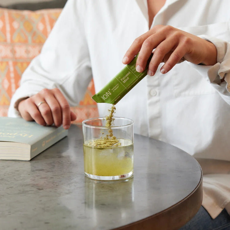 Person pouring a packet of ION Focused Mind into a glass of water