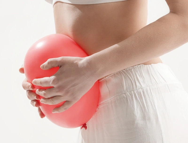Woman holding balloon in front of abdomen